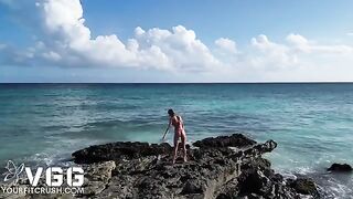 A pretty woman is naked on the beach and caresses her body