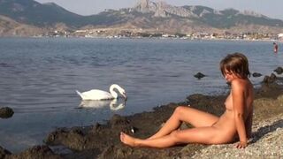 A naked girl is having fun on the riverbank, capturing moments of joy