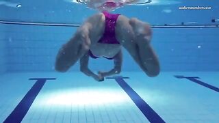 Nude beauty has fun in the swimming pool, showcasing her body