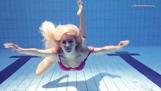 Nude beauty has fun in the swimming pool, showcasing her body