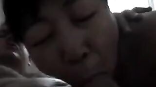 An adult Chinese woman practices her blowjob skills on a man