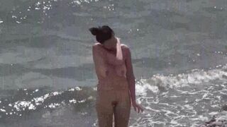 A couple of free-spirited nudists enjoy each other's company on the beach