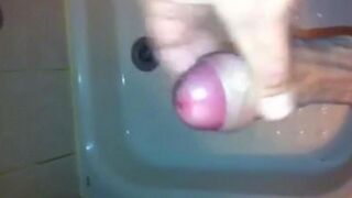 The kid masturbates his dick with his hand while standing in the shower