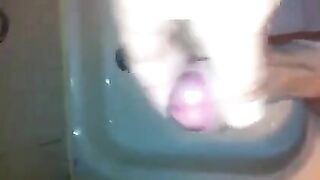 The kid masturbates his dick with his hand while standing in the shower
