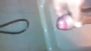 The kid masturbates his dick with his hand while standing in the shower