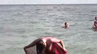 A naked girl bathes in the sea, exposing her body